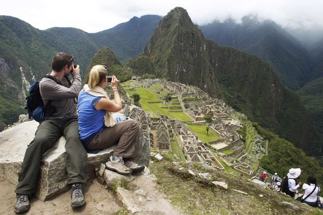 A tourist couple takes pictures of Inca's citadel of Machu Picchu in Cuzco